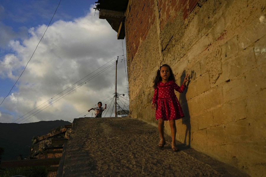 Two children run and walk on a steep sidewalk.