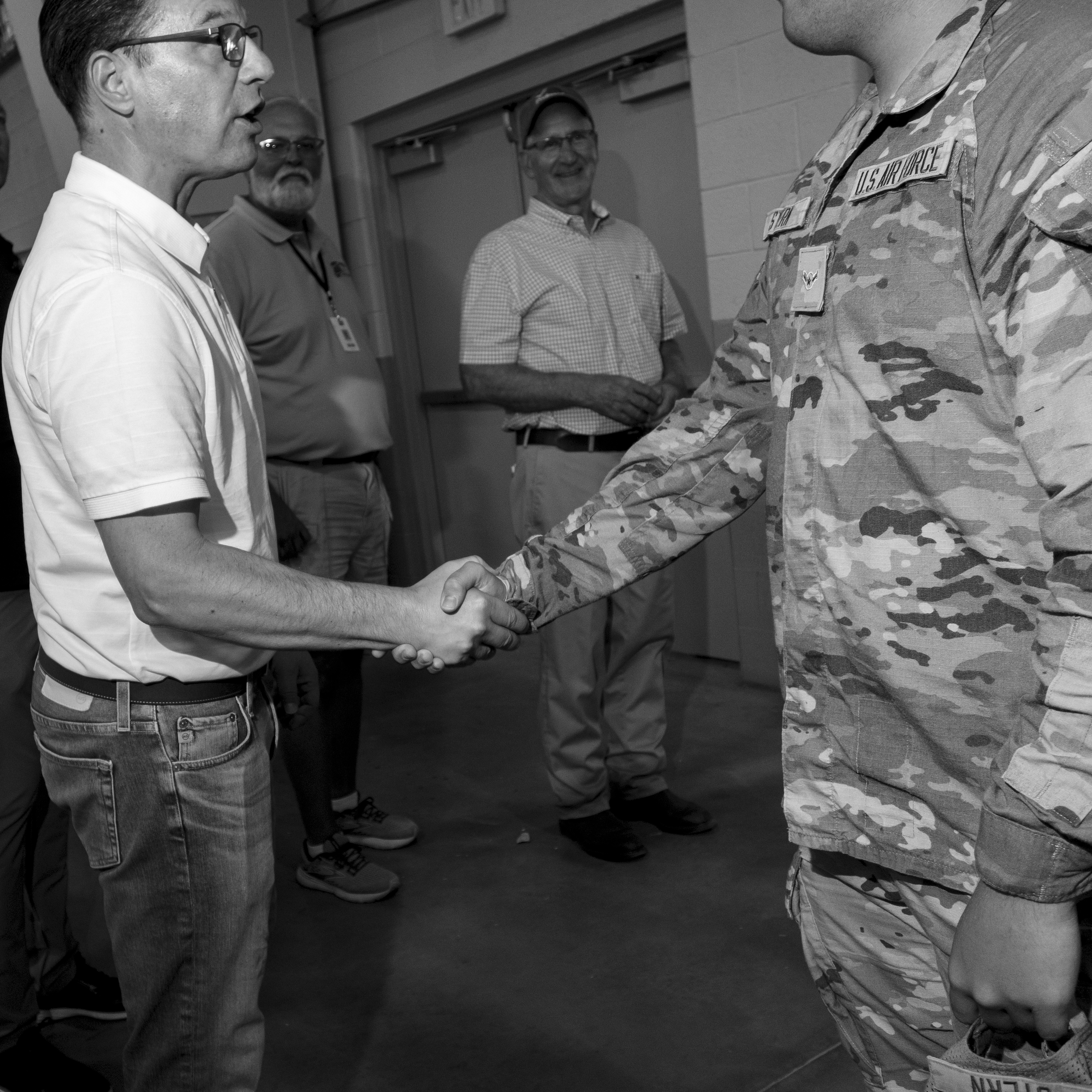 A black and white photograph of Josh Shapiro shaking hands with a man in US military fatigues