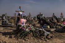 Rows of crosses for the Ukrainian victims of a Russian bomb attack. One cross has an image of a girl and a pink teddy bear underneath.