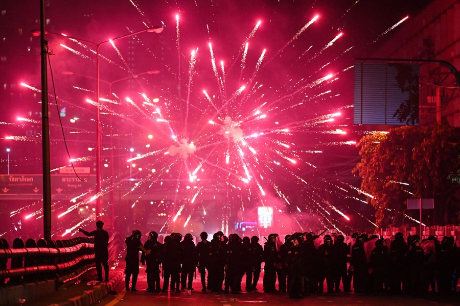Fireworks explode above a group of riot police.