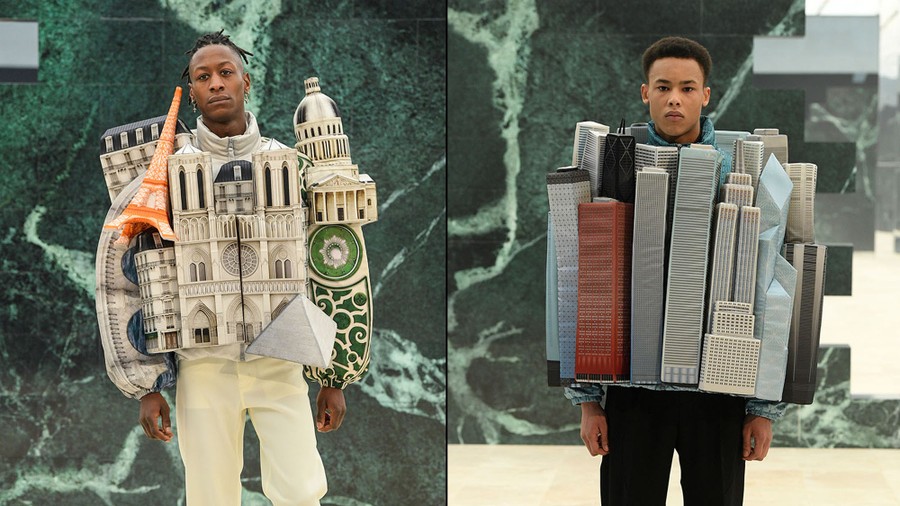 Two male models display outfits shaped like clusters of buildings.