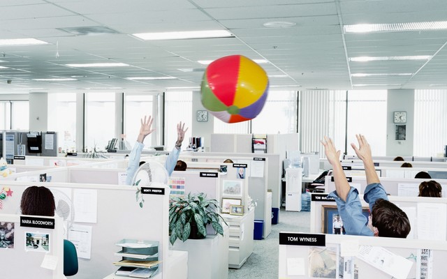 Workers throw a beachball in an office.