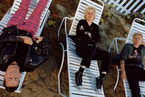 the three members of green day lying on white lawn chairs