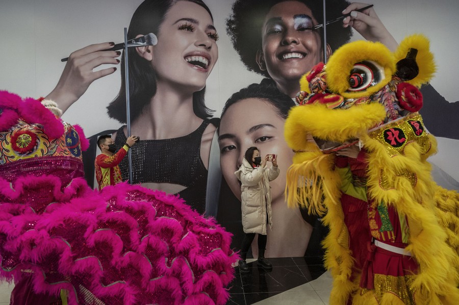 People take photos as Lion dance performers dance in a shopping mall.