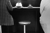 An empty stool in between two people at a dining establishment