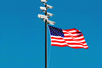 A flagpole with surveillance cameras at the top and an American flag waving