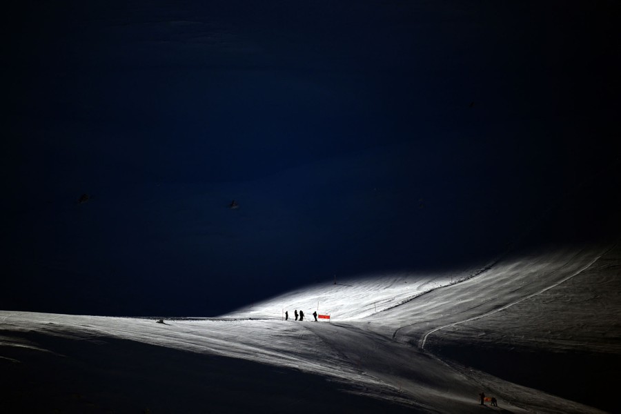 A distant view of several skiers on a broad snow-covered slope