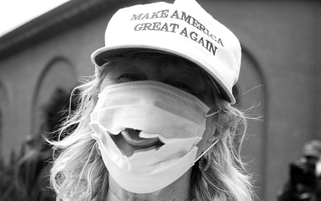 A woman wearing a Make America Great Again hat and a mask with a hole.