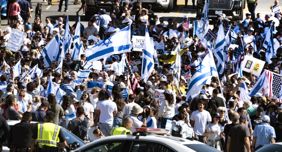 A crowd of pro-Israeli protesters wave flags.