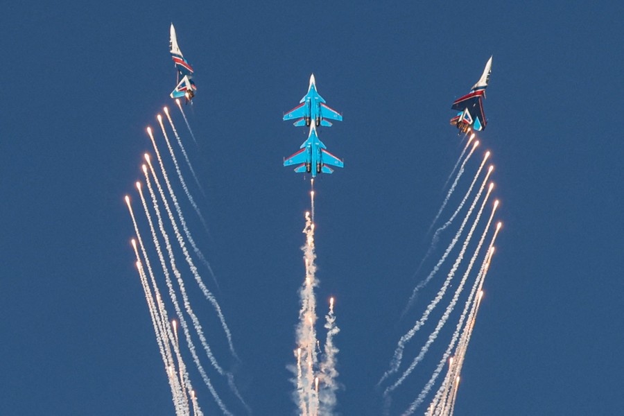 Four military jets perform aerobatics while releasing flares.
