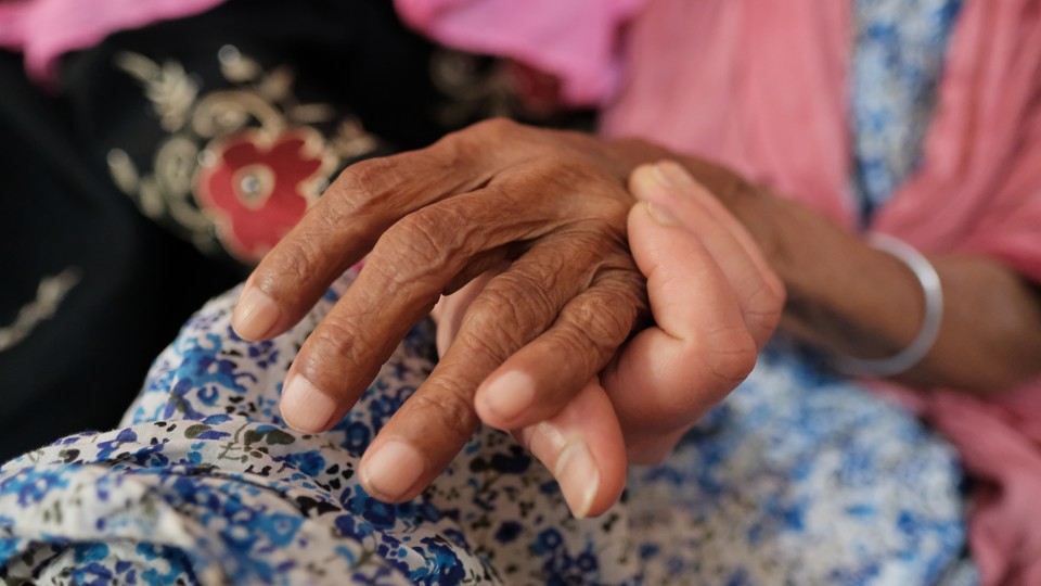 young hand underneath elderly hand