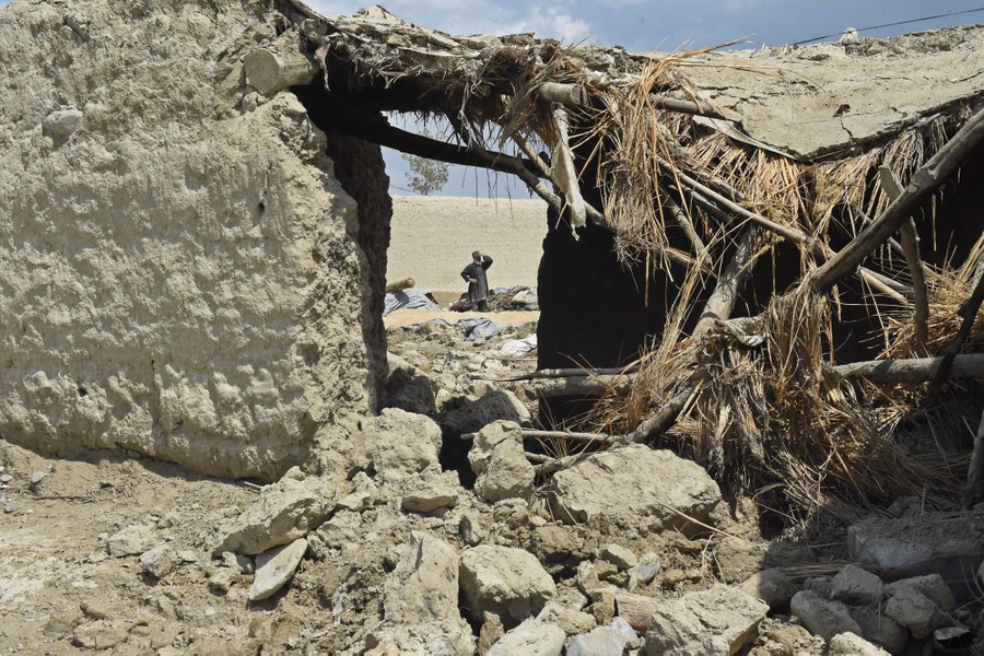 A person stands outside a flood-damaged house.