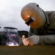 A welder works with a small torch and helmet on.