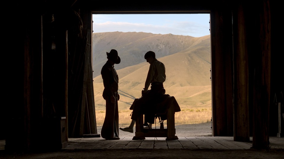 A silhouette of two men in a barn