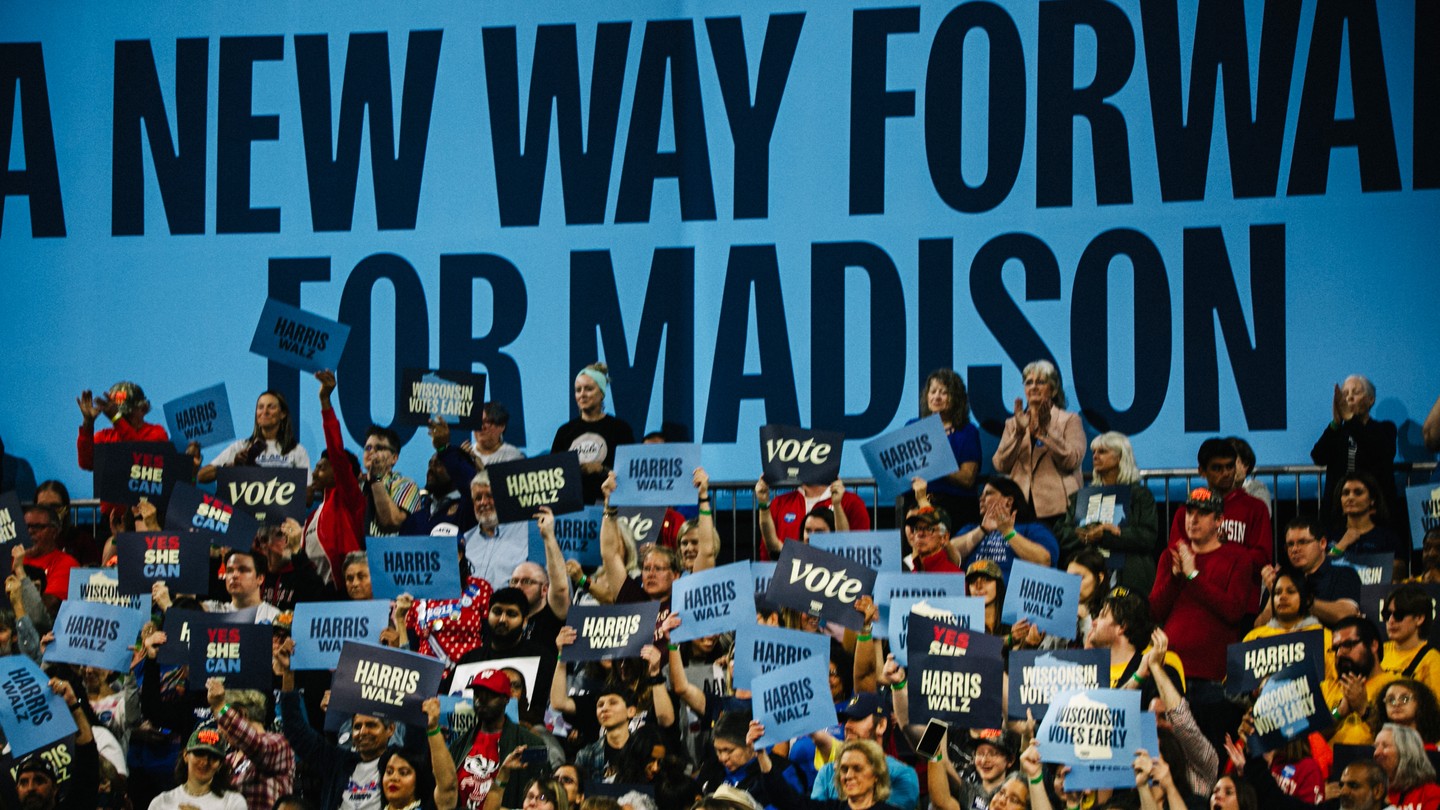 People hold blue Harris-Walz signs at a rally