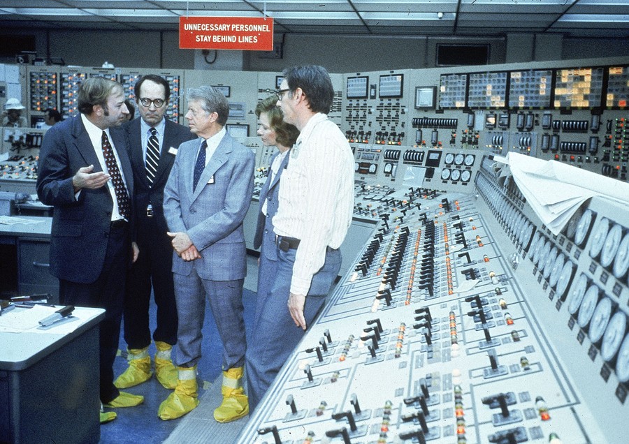 President and Mrs. Carter stand with three others in a control room for a nuclear-power plant.