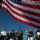Framed by an American flag, immigrants raise their right hands and take the oath of allegiance during a naturalization ceremony.