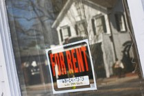 A "for rent" sign hangs in the window of a home.