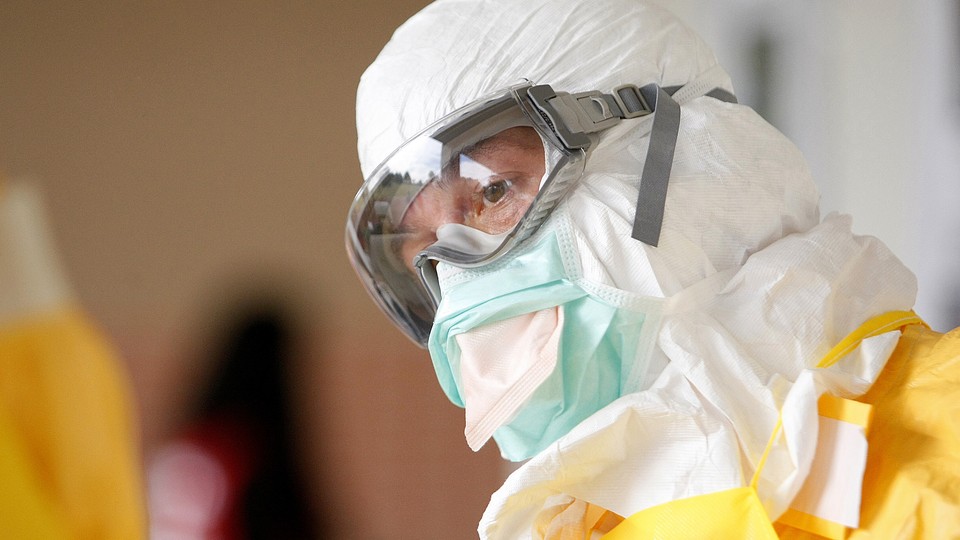 A person wearing a full protective suit, googles, and a surgical mask