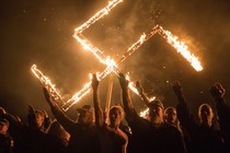 Supporters of the National Socialist Movement give Nazi salutes while taking part in a swastika burning.