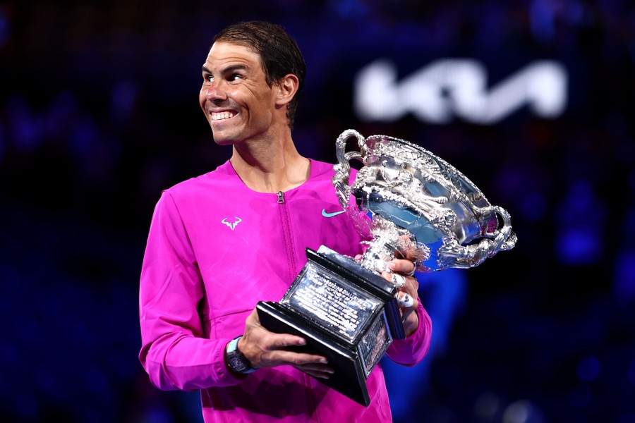 Tennis player Rafael Nadal stands with a large silver trophy.