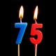 two birthday candles, a blue seven and a red five, are lit with high flames.