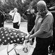 A man wheels the flag-covered body of a firefighter who died of COVID-19 past saluting officers.