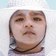 A child in a white hat with lots of sunscreen on her face