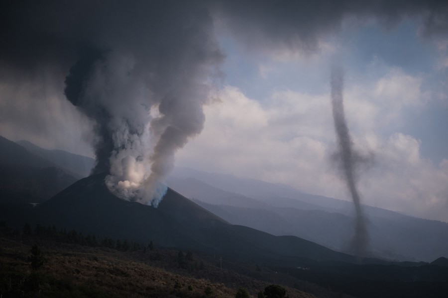 A narrow funnel cloud draws bits of ash into the air near the volcano's summit.