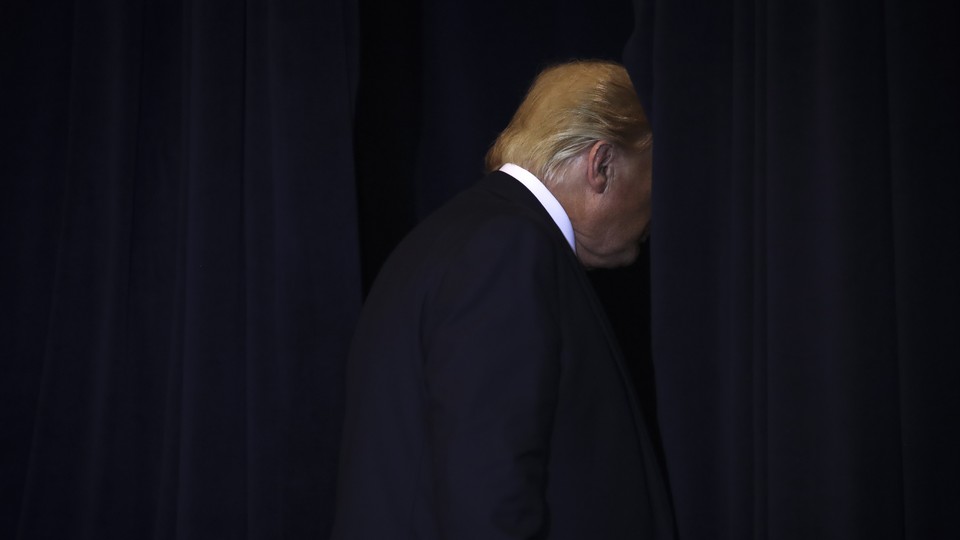President Donald Trump walks through a parted curtain