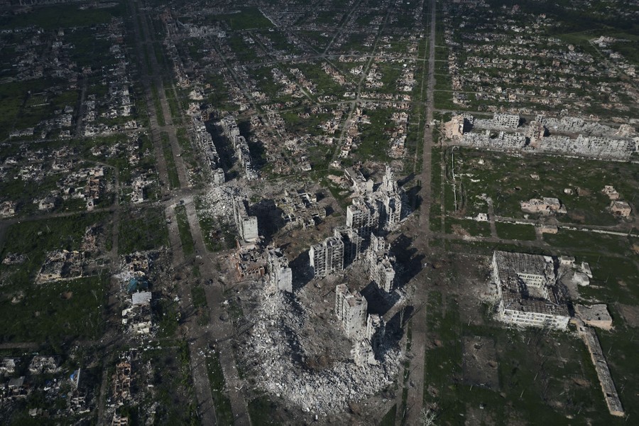 An aerial view of a heavily war-damaged city, with many buildings reduced to rubble.