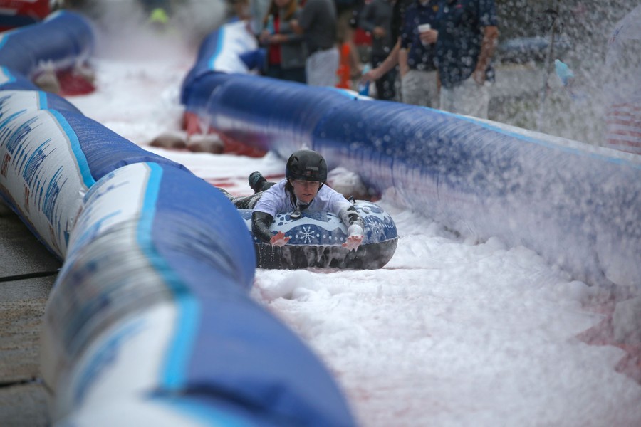 A person slides down a very long chute on a small inflatable raft.
