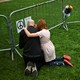 A father and two of his children hug while kneeling on a grass field outside the scene of the Boulder, Colorado, attack