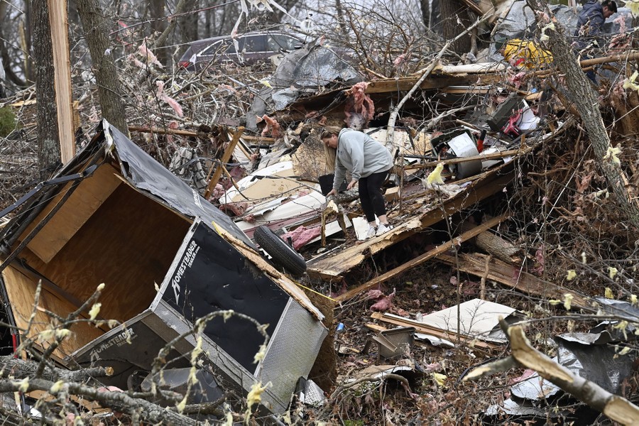 A person picks through the debris of a house and broken branches, the aftermath of a tornado.