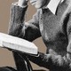 A man in a sweater reading a book, with only the lower half of his face showing