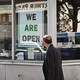 A man walking past a storefront with a “We are open sign.”