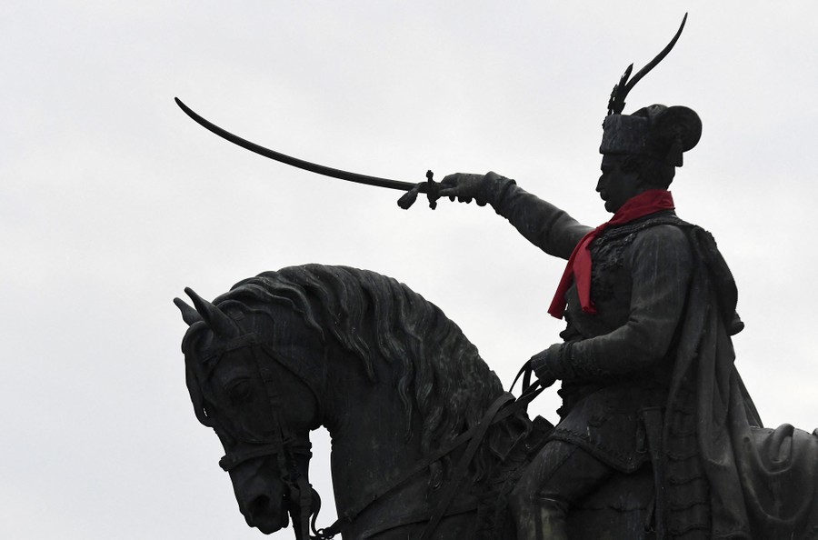 A statue of a horse and rider. The rider holds a sword and has a red cloth scarf tied around his neck.