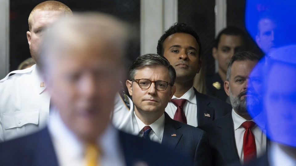Speaker of the House Mike Johnson, businessman Vivek Ramaswamy, and Representative Cory Mills stand behind Trump as he speaks to the media