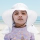 A child in a white hat with lots of sunscreen on her face