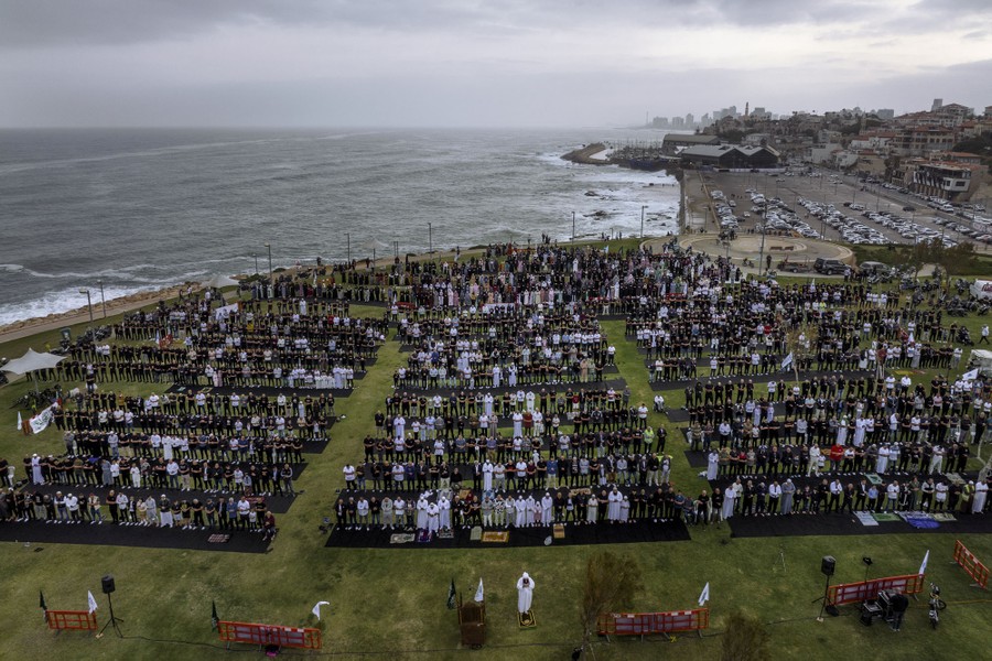 An aerial view of a group of worshippers praying in a seaside park