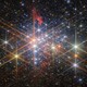 Hundreds of bright and differently colored stars, seen in a cluster, with most stars displaying six long diffraction spikes, artifacts of the telescope's structure