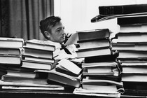 a black and white photo of William F. Buckley sitting at a desk surrounded by books
