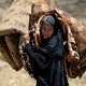 An Iraqi woman carries a mattress and a blanket while she flees her home in Mosul in 2017