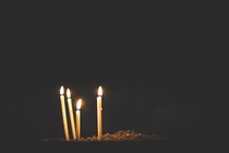 Four candles burn against a dark backdrop.