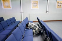A woman on her knees amid rows of blue chairs