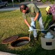 Officials collect a wastewater sample from a Montana State University sewage line.
