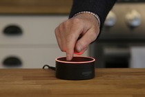 A man mutes an Amazon Echo Dot