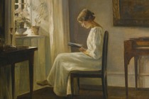 A woman reads next to a window