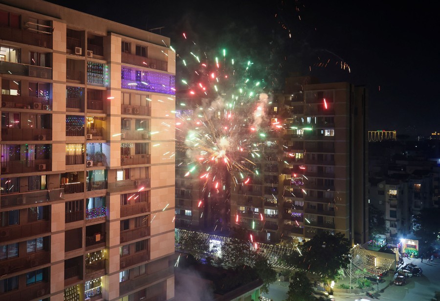 Fireworks explode in front of a residential building.