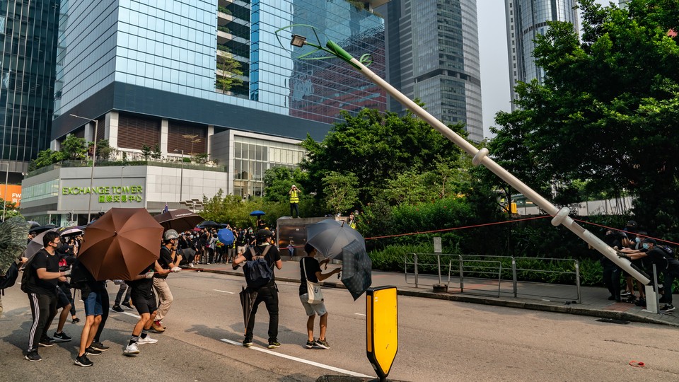 Protesters in Hong Kong take down a lamppost